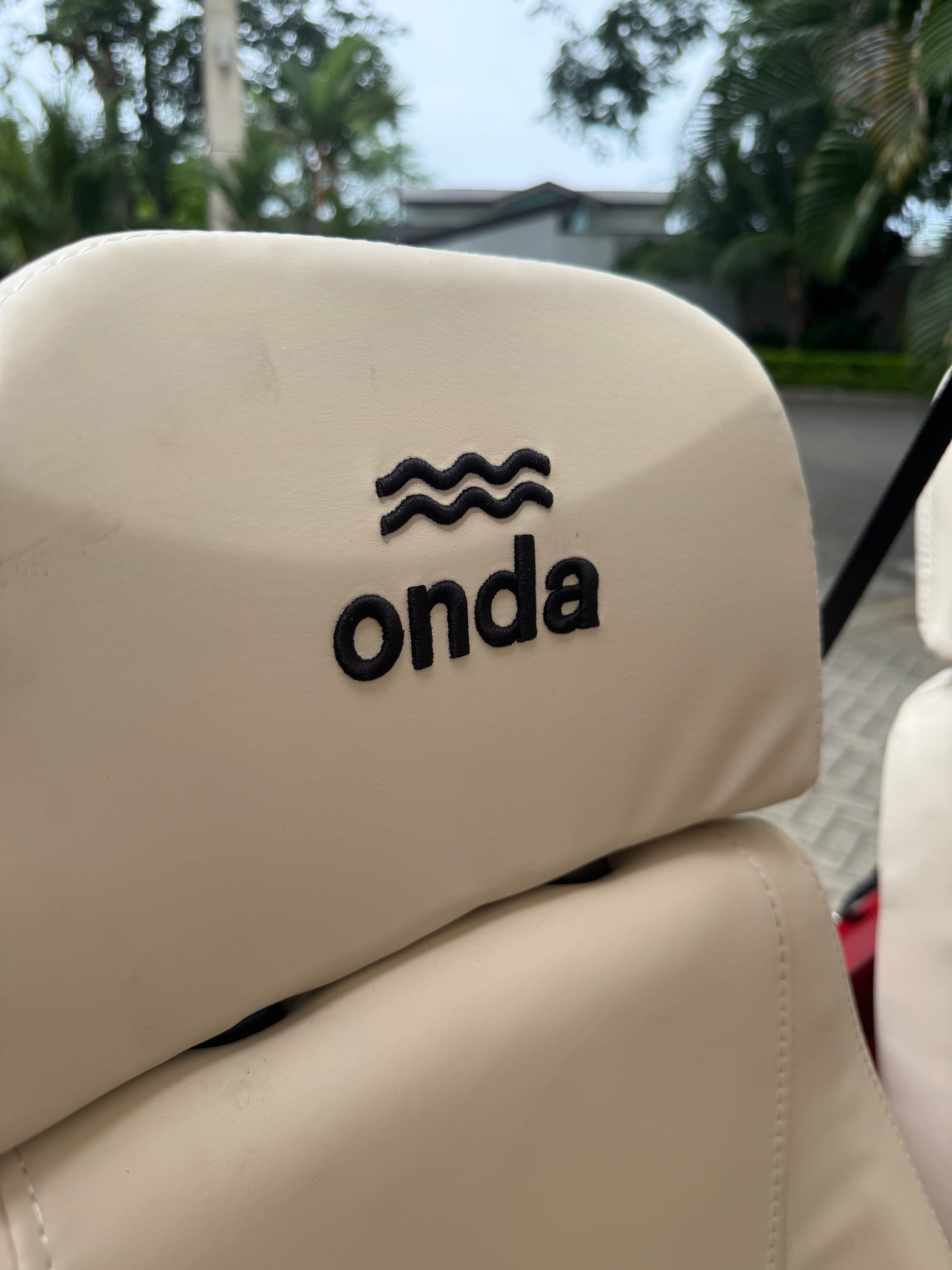 Beige car seat with 'onda' logo on a blurred outdoor background